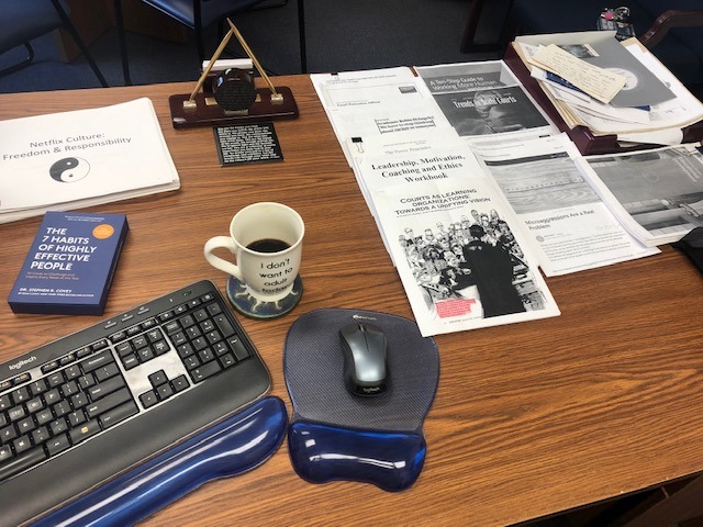 Desktop with coffee, keyboard, mouse, books, and papers