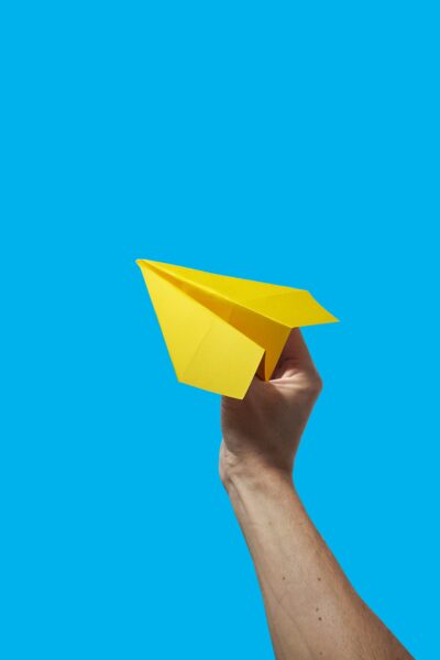 paper airplane in hand blue background